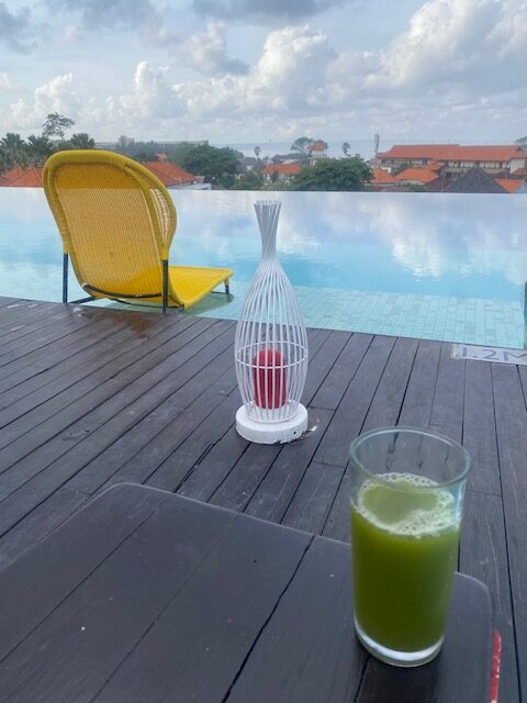 Green juice by the pool – alcohol and fat loss Glass of green juice on a poolside table, a non-alcoholic option when tracking your drinks for weight loss