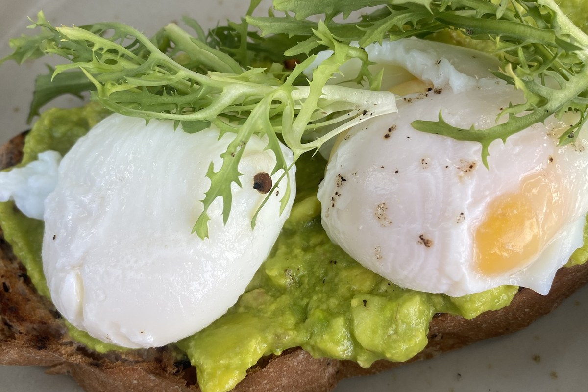 High protein breakfast: poached eggs on avocado sourdough toast Two poached eggs on smashed avocado and sourdough toast, topped with fresh leaves