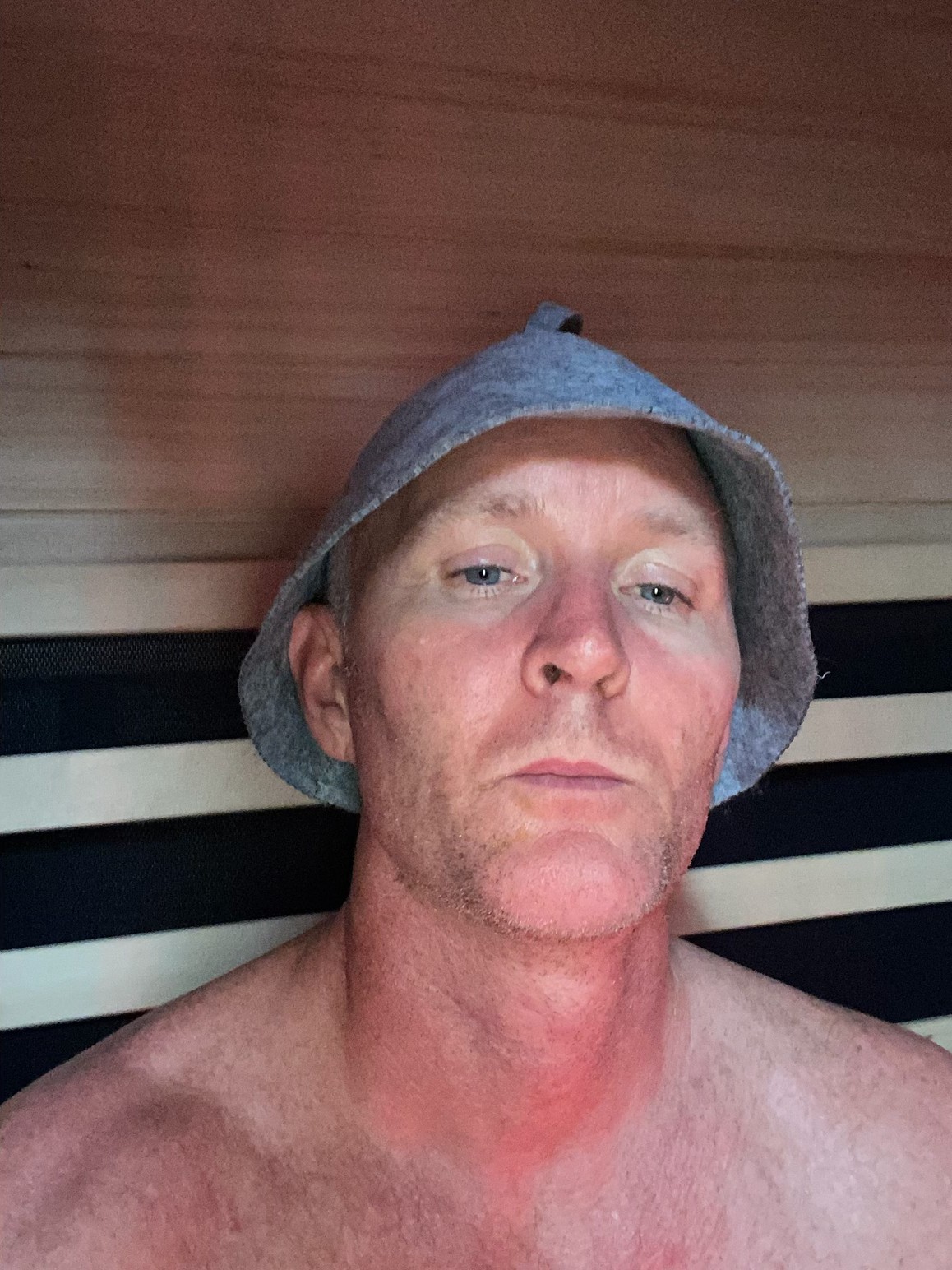 Sleep and recovery: Zak in an infrared sauna Zak relaxing in an infrared sauna in a felt sauna hat, recovering after training.