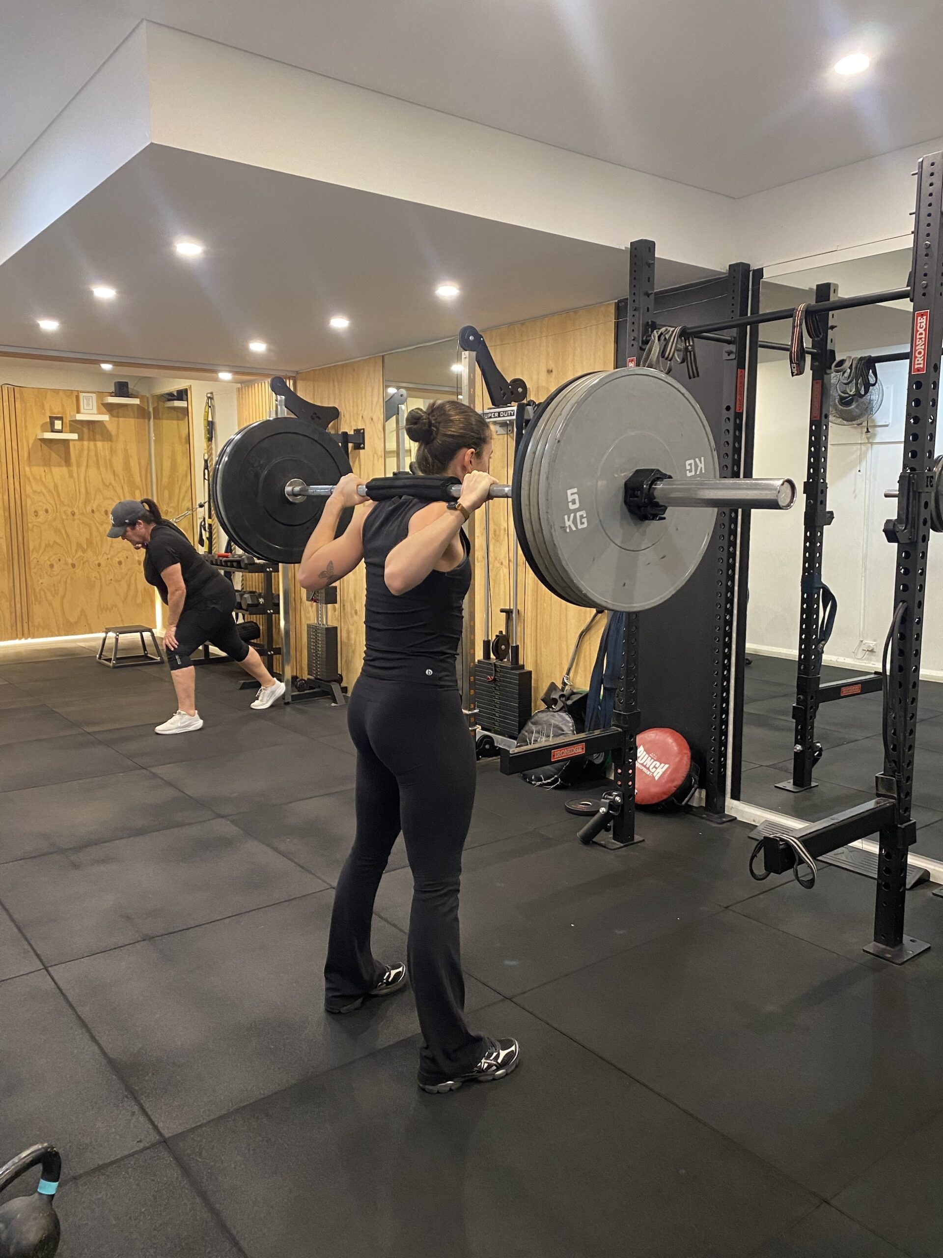 Squats with sore knees: barbell back squat at The Fitness Space, Maroubra Client setting up a barbell back squat at The Fitness Space studio in Maroubra